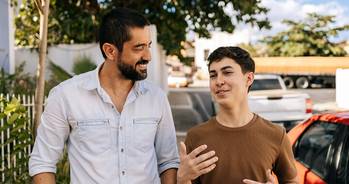 A man and a teenage boy walking and talking outdoors